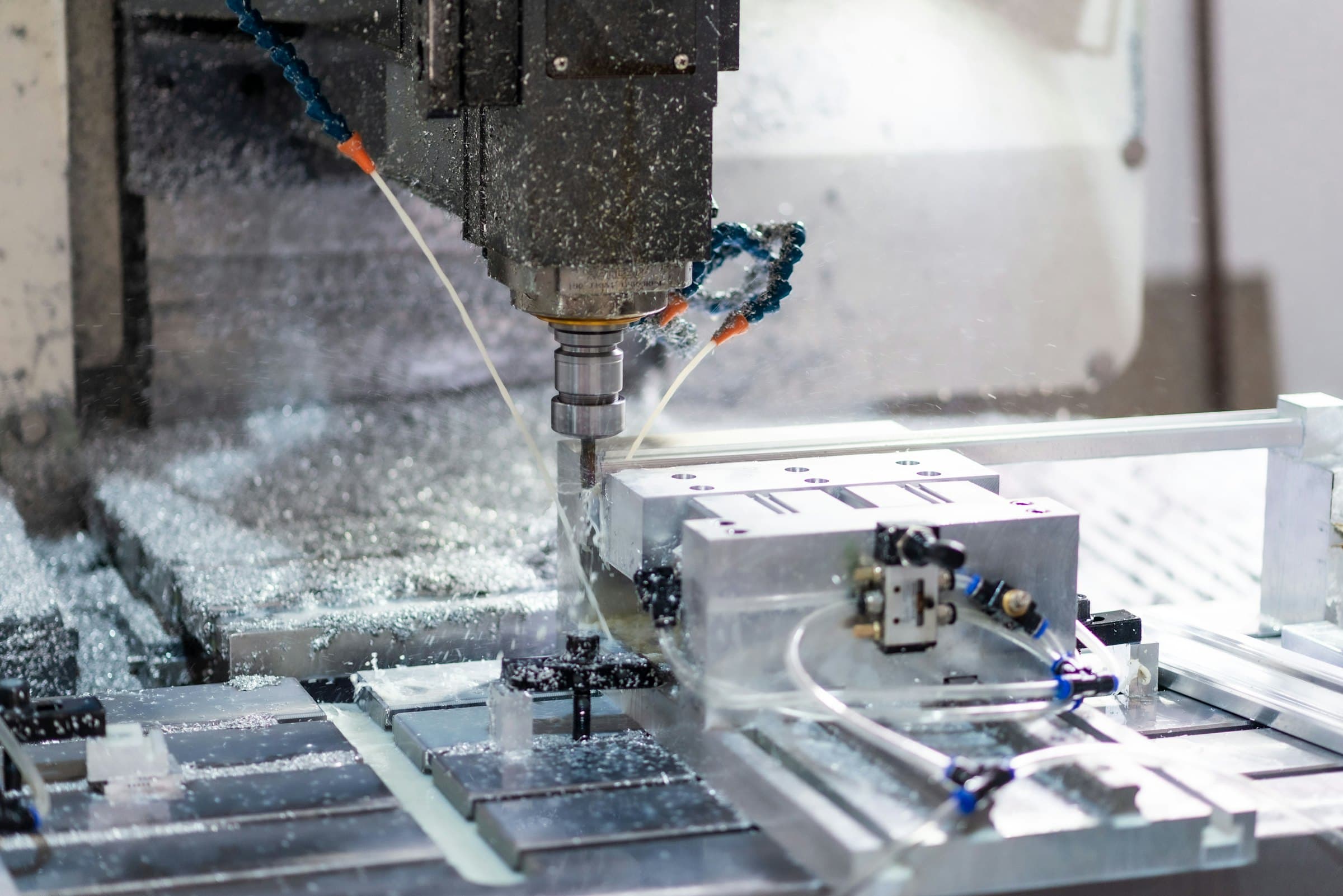 Ax de frezare CNC prelucrând o piesă din aluminiu, cu furtunurile de răcire vizibile